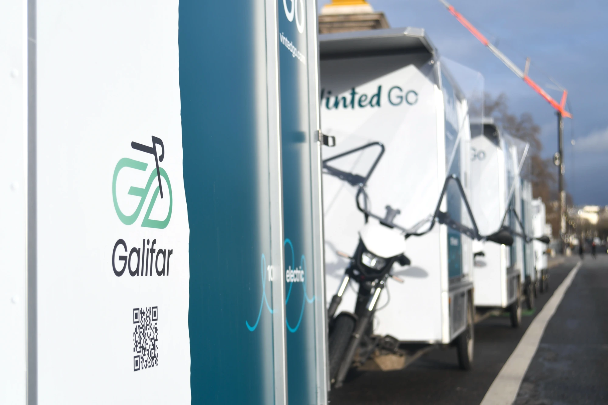 Branding Galifar au premier plan, convoi de vélos cargos Vinted Go alignés dans une rue parisienne