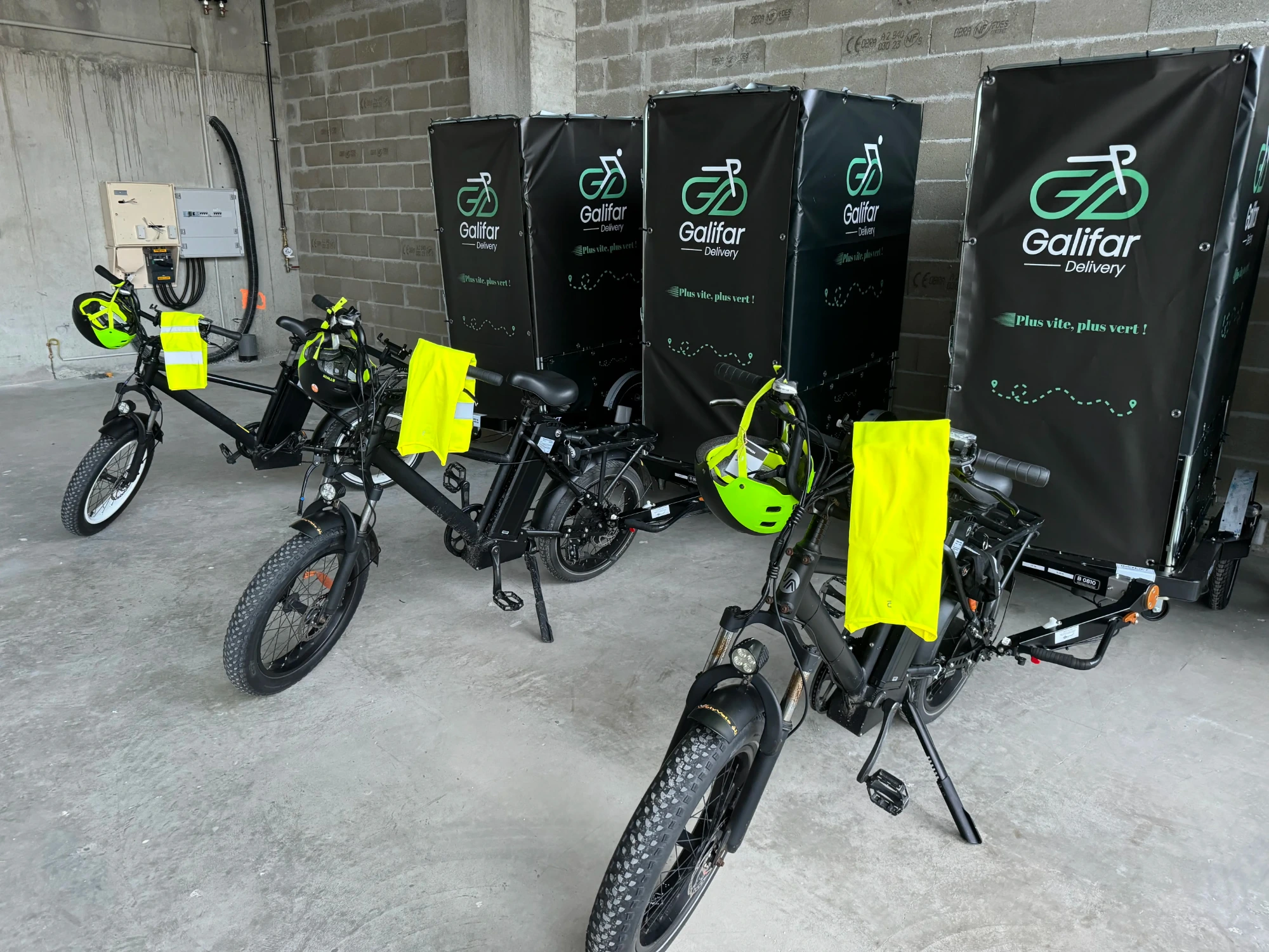 Vélos cargos électriques Galifar Delivery alignés dans le hub, caissons brandés